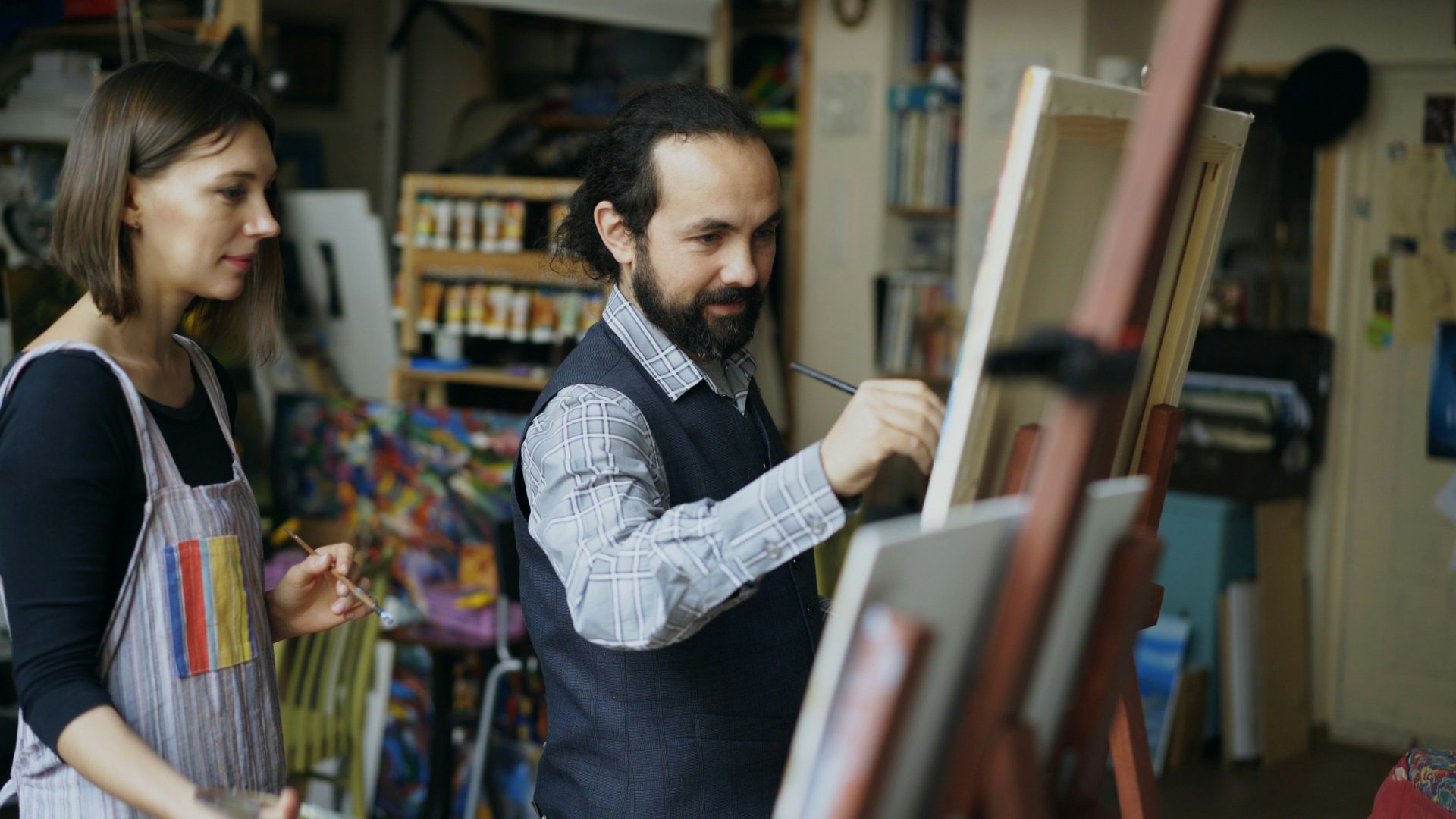 Artist teaching student painting in studio